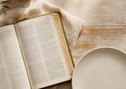 An empty plate beside an open Bible and candle, representing fasting as surrender rather than restriction.