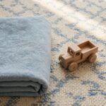 A child's toy truck resting on a tidy rug beside a folded blanket, representing order taught through care rather than fear.