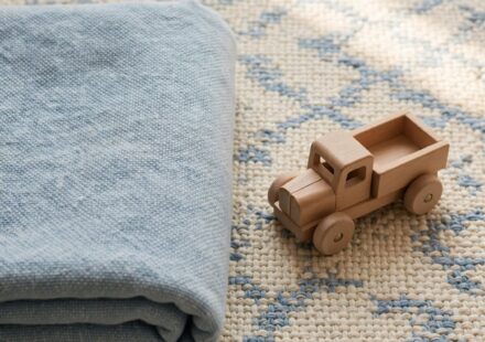 A child's toy truck resting on a tidy rug beside a folded blanket, representing order taught through care rather than fear.