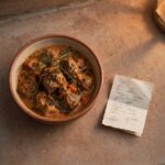 A warm meal dish on a doorstep beside a handwritten note, representing an unplanned moment of grace showing up uninvited.