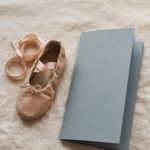 A child's dance shoe beside a folded, unused recital program, representing a disappointment felt honestly rather than rescued away.