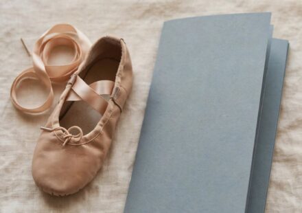 A child's dance shoe beside a folded, unused recital program, representing a disappointment felt honestly rather than rescued away.