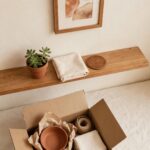 A freshly hung picture and half-unpacked box in a small apartment corner, representing a temporary space fully received as a real home.