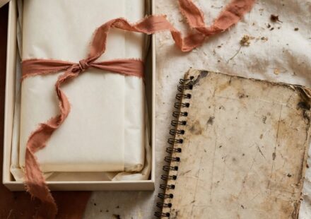 An unopened gifted planner beside a worn, well-used notebook, representing the tension between a loving gift and what actually works.