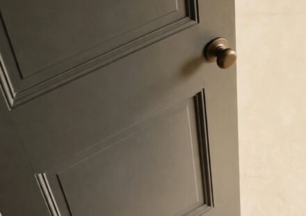 A closed bathroom door with a child's small hands visible at the bottom, representing a parent's rare, interrupted moment of rest.