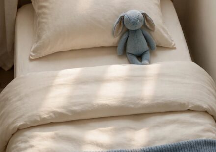 A neatly made child's bed with a single stuffed animal on the pillow, representing the quiet grief of a home now empty of daily presence.