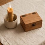 A candle beside a small closed box, representing words kept carefully rather than spent carelessly.
