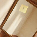 A small sticky note on a mirror corner, representing a pause taken before saying yes to a new commitment.