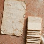 A worn recipe card beside a small stack of notes on a kitchen counter, representing a role repeated for years without ever being revisited.