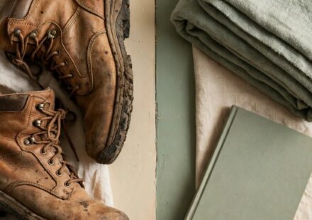 Hiking boots on one side of a table and a book with a blanket on the other, representing two different but equally valid ways to rest.