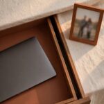 A closed laptop placed in a drawer beside a visible family photo, representing a genuine boundary between work and home life.