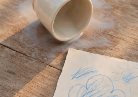 An overturned cup with a milk stain beside a child's drawing, representing a small moment repaired through a parent's honest apology.