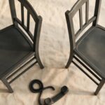 A phone receiver resting between two chairs facing away from each other, representing the weight of standing between two people's conflict.
