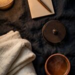 What to Do When You Wake Up at 3 A.M. and Cannot Fall Back Asleep A small notepad and pen rest on a nightstand beside a face-down clock and a terracotta mug in soft lamplight.