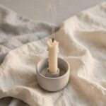 A birthday candle just blown out with smoke still rising, representing a good moment felt from a strange emotional distance.